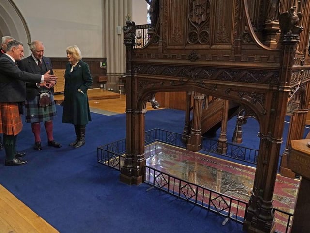 King Charles III and the Queen Consort are shown the grave stone of Robert the Bruce during a visit to Dunfermline Abbey