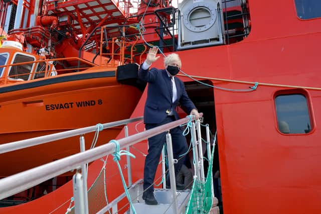 Prime Minister Boris Johnson waves as he boards the vessel Alba in Fraserburgh Harbour, Aberdeenshire, which will transport him to the Moray Offshore Windfarm East during his visit to Scotland.