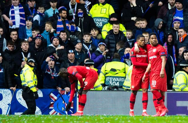 Bayer Leverkusen's Moussa Diaby (L) picks up a bottle during the Europa League last 16 first leg against Rangers at Ibrox.