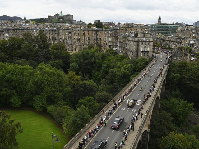 The hearse carrying the coffin of Queen Elizabeth II, draped with the Royal Standard of Scotland, passing through the outskirts of Edinburgh as it continues its journey to the Palace of Holyroodhouse from Balmoral. Picture date: Sunday September 11, 2022.