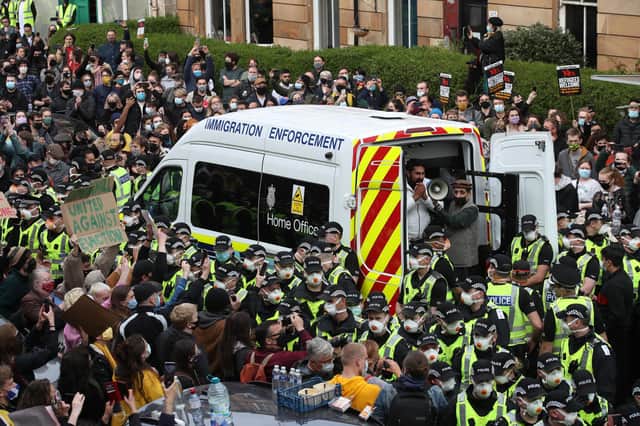 One of two men are released from the back of an Immigration Enforcement van accompanied by Mohammad Asif, director of the Afghan Human Rights Foundation, in Kenmure Street, Glasgow which is surrounded by protesters. Picture date: Thursday May 13, 2021.