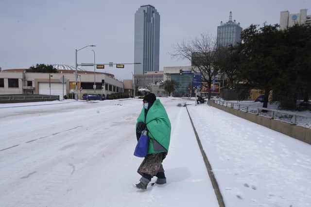 A woman wrapped in a blanket crosses a street near downtown Dallas in Texas, where snow and ice caused much of the power grid to collapse and also affected water supplies (Picture: LM Otero/AP)
