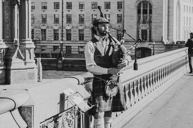 “A bagpiper performs on Westminster Bridge, echoing the enduring global appeal of Scottish musical traditions now influencing digital licensing trends.”