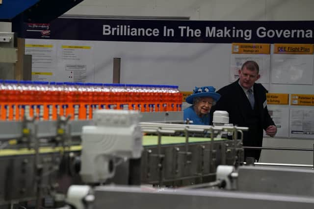 Queen Elizabeth II with Chief Executive Roger White in the bottling plant during a visit to AG Barr's factory in Cumbernauld.