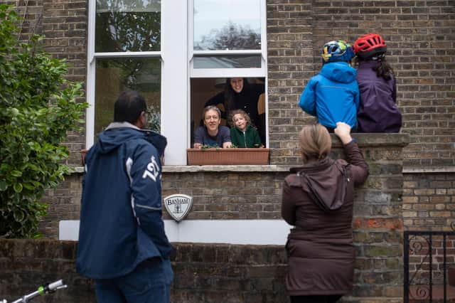 Two families maintain social distancing while talking to each other outside a home in Hampstead, north London, as the UK continues in lockdown to help curb the spread of the coronavirus.