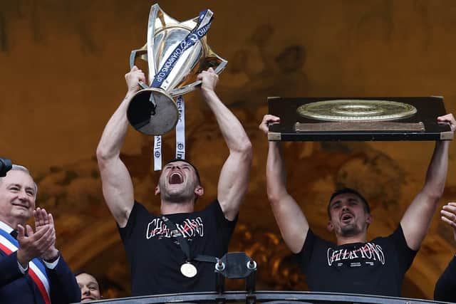 Toulouse's Scottish full-back Blair Kinghorn holding the European Rugby Champions Cup trophy and Toulouse's French fly-half Thomas Ramos holding the "Bouclier de Brennus" Top 14 trophy as they celebrate with supporters.  (Photo by VALENTINE CHAPUIS/AFP via Getty Images)