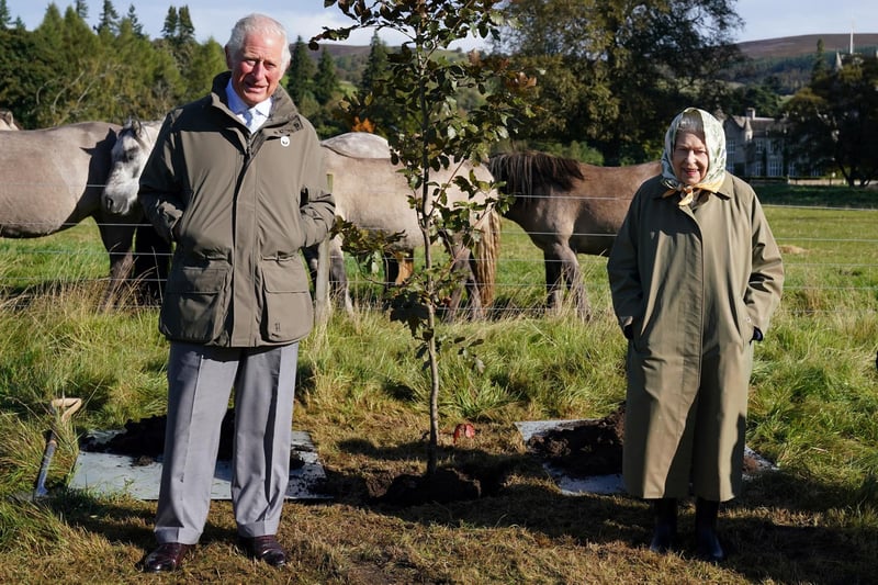 Queen Elizabeth II and Prince Charles pose alongside the tree which they planted to mark the start of the official planting season for the Queen's Green Canopy at the Balmoral Cricket Pavilion on October 1, 2021.