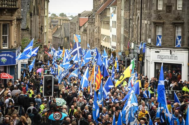 Pro-independence activists wave Scottish Saltire flags as they march from Holyrood to the Meadows in Edinburgh