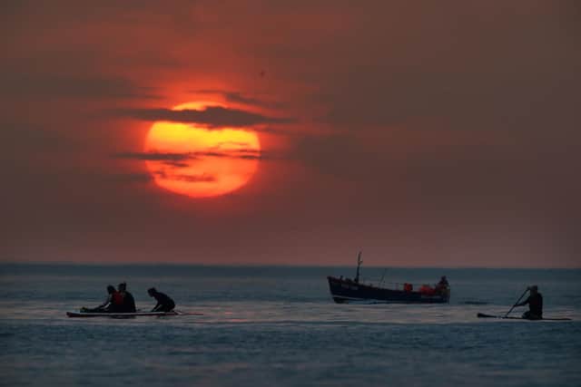 Paddleboarders turn out to watch the sunrise at Cullercoats Bay, North Tyneside. Britons are set to melt on the hottest UK day on record as temperatures are predicted to hit 40C. Picture date: Tuesday July 19, 2022.