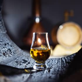A glass of whisky in old oak barrel