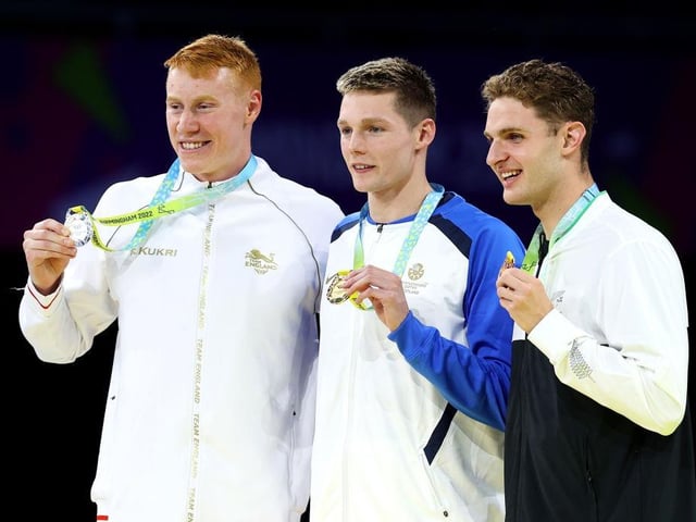 Scottish swimmer Duncan Scott receives his gold medal in the Men's 200m Individual Medley alongside silver medalist, Tom Dean of England and bronze medalist, Lewis Clareburt of New Zealand.