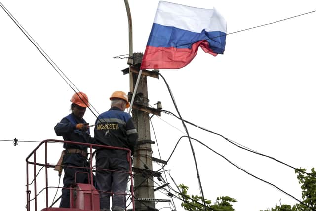 Municipal workers attach a Russian national flag to a pole preparing to celebrate 77 years of the victory in WWII in Mariupol, in territory under the government of the Donetsk People's Republic, eastern Ukraine, Thursday, May 5, 2022.  (AP Photo)