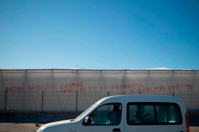 A car drives past a graffiti on a greenhouse reading 'Franco is not the problem, the problem is you' in El Ejido, Almeria (Picture: Jorge Guerrero/AFP via Getty Images)