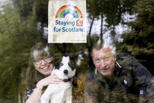 Colin and Margaret Moncur, with their dog Molly, look out from their window in Minard, Argyll and Bute. A handful of residents in the village set up a community group to help the vulnerable with shopping with the majority of those in the village now assisting