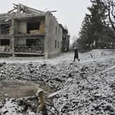 A local resident walks past a crater and a damaged residential building following a recent aerial bombardment in Kupiansk, Kharkiv region.