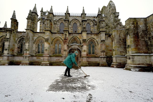 A person clears the pathway at Rosslyn Chapel