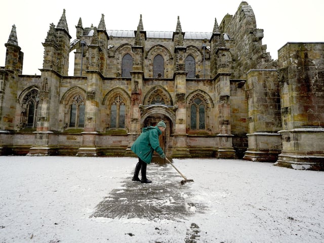 A person clears the pathway at Rosslyn Chapel