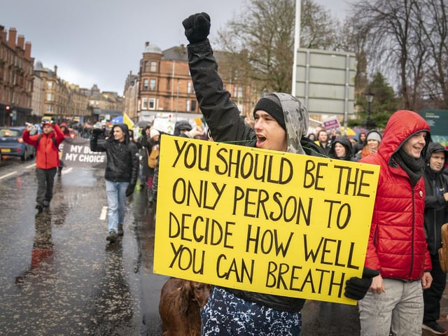 Another person taking part in the protest carrying a sign which says: "You should be the only person to decide how well you can breathe".