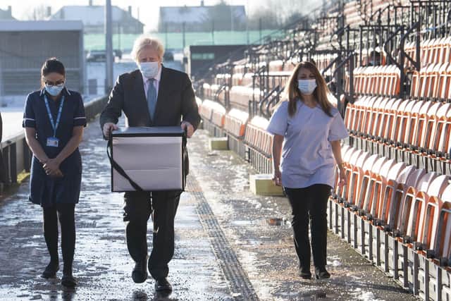 Prime Minister Boris Johnson carries Oxford AstraZeneca COVID-19 vaccine for mobile distribution during a visit to Barnet FC's ground at the Hive. Picture: Stefan Rousseau/Pool Photo via AP