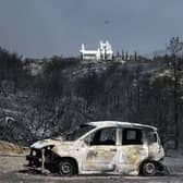 TOPSHOT - A burnt car in a charred area after a fire near the village of Kiotari, on the Greek island of Rhodes. Tens of thousands of people have already fled blazes on the island of Rhodes, with many frightened tourists scrambling to get home.