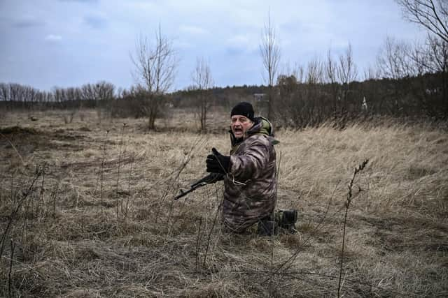 A Ukrainian soldier takes cover as people flee the city of Irpin, west of Kyiv (Picture: Aris Messinis/AFP via Getty Images)