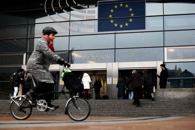A woman rides near the entrance of the European Parliament in Brussels.