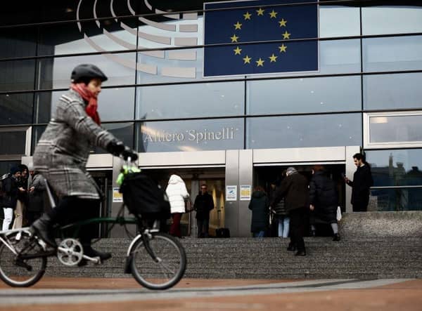 A woman rides near the entrance of the European Parliament in Brussels.