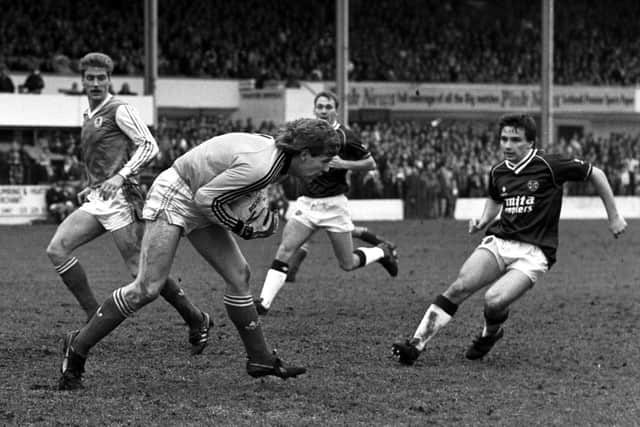 Hibs goalkeeper Andy Goram takes possession as Hearts winger John Colquhoun looks on during a goalless Edinburgh derby in March 1988