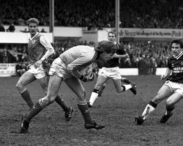 Hibs goalkeeper Andy Goram takes possession as Hearts winger John Colquhoun looks on during a goalless Edinburgh derby in March 1988