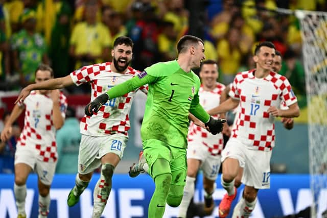 Croatia goalkeeper Dominik Livakovic is chased by his teammates after the penallty shoot-out win over Brazil in the World Cup quarter-final. (Photo by GABRIEL BOUYS/AFP via Getty Images)