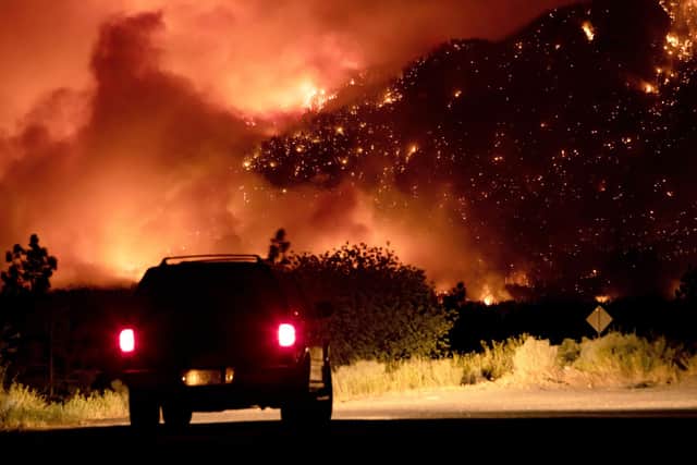 A motorist watches as a wildfire burns on the side of a mountain in Lytton, British Colombia, Canada (Picture: Canadian Press/Shutterstock)