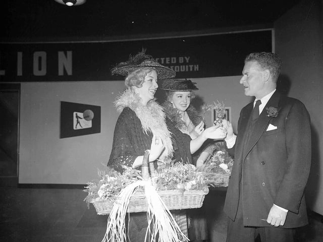 Anthony Asquith receives heather from Susan Parar and Elizabeth 'Pygmalion' Griffith at the Rank Organisation's 21st birthday celebration in the New Victoria Cinema during the festival in 1956.