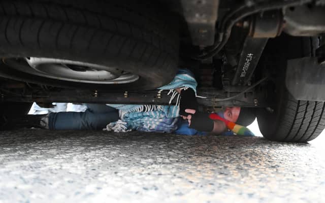 One protester has wedged himself under the van to stop it driving away.