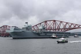 HMS Queen Elizabeth leaving Rosyth in Fife, Scotland, and sailing under the Forth bridge.