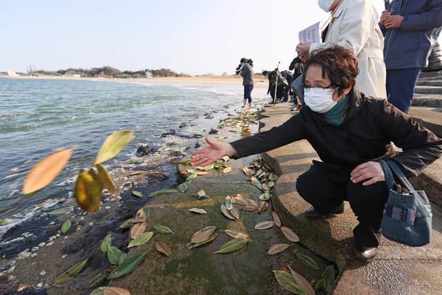 A woman throws leaves bearing messages to loved ones into the sea at Soma, Fukushima, on March 11, the 10th anniversary of the earthquake, tsunami and nuclear power plant disaster (PIcture: Jiji Press/AFP via Getty Images)