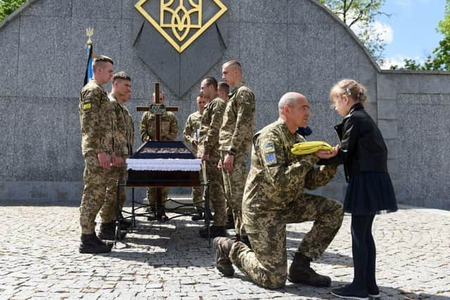 A serviceman offers the Ukrainian flag to the daughter of Yuriy Huk, a Ukrainian serviceman, killed during the Russian invasion of Ukraine, at his funeral service at the Saints Peter and Paul Garrison Church, in the western Ukrainian city of Lviv. Picure: Yuriy Dyachyshyn/AFP via Getty Images