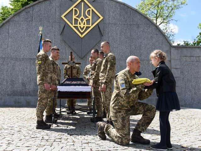 A serviceman offers the Ukrainian flag to the daughter of Yuriy Huk, a Ukrainian serviceman, killed during the Russian invasion of Ukraine, at his funeral service at the Saints Peter and Paul Garrison Church, in the western Ukrainian city of Lviv. Picure: Yuriy Dyachyshyn/AFP via Getty Images