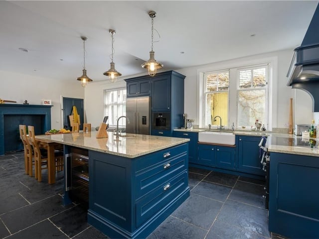 The kitchen has a large central island, painted timber cabinets and lots of space for a dining table or comfortable seating.