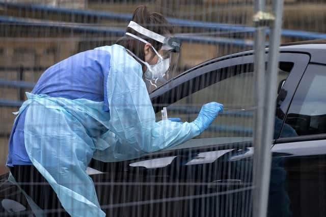 A health worker offers a swab through a car window at a 'drive-through' coronavirus testing facility at the Western General Hospital in Edinburgh.