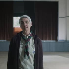 A screenshot of the party political broadcast including a woman in full Scout uniform