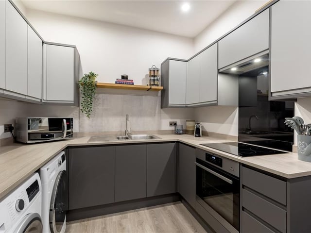 Utility room with further cooking facilities, storage units and plumbing for a washing machine.