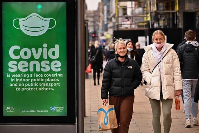 Members of the public walk along Princess Street, with a Covid warning advert in the foreground. Picture: Jeff J Mitchell/Getty Images