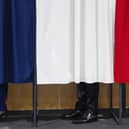 France's President Emmanuel Macron, flanked by his wife Brigitte Macron, in a polling booth, adorned with curtains displaying the colors of the flag of France (Pic: Mohammed Badra/Pool/ AFP)
