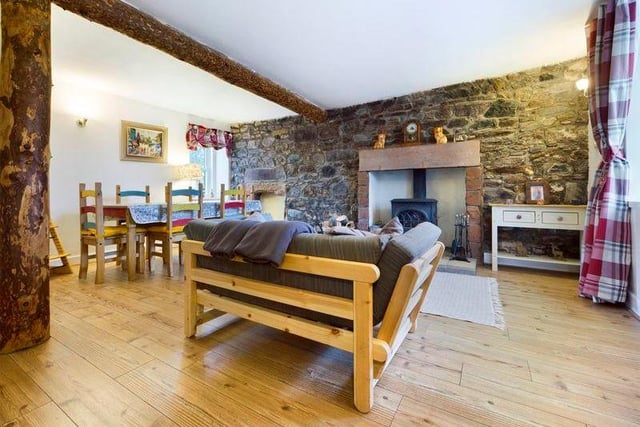 The open plan lounge/dining room is a striking room with an exposed stone wall housing the fireplace and cosy stove.