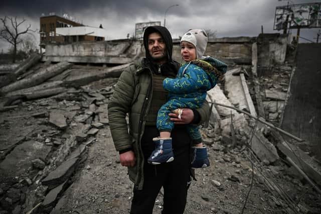 A man holds a child as he flees the city of Irpin, west of Kyiv, on March 7 (Picture: Aris Messinis/AFP via Getty Images)