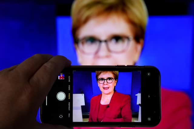 A person uses their phone to film a televised broadcast of First Minister Nicola Sturgeon speaking to MSPS during a virtual sitting of the Scottish Parliament. Picture date: Tuesday August 3, 2021.