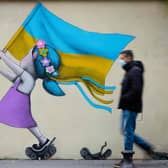 A bystander walks past a fresco by street artist Seth depicting a girl with a Ukrainian flag walking on tanks in Paris. Picture: Joel Saget/AFP via Getty Images