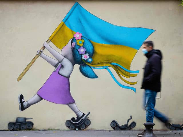 A bystander walks past a fresco by street artist Seth depicting a girl with a Ukrainian flag walking on tanks in Paris. Picture: Joel Saget/AFP via Getty Images