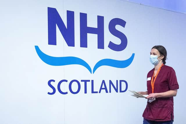 A member of the vaccination team walks past an NHS sign at the coronavirus mass vaccine centre at the Edinburgh International Conference Centre earlier this year. Picture: Jane Barlow - Pool/Getty Images