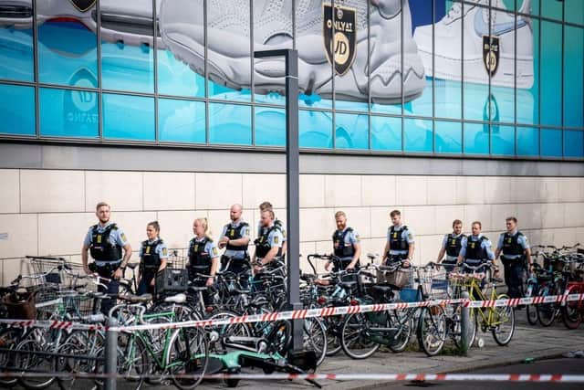 Police stand on the site of the Fields shopping mall, in Copenhagen, one day after a deadly shooting which left three people dead and several others wounded.